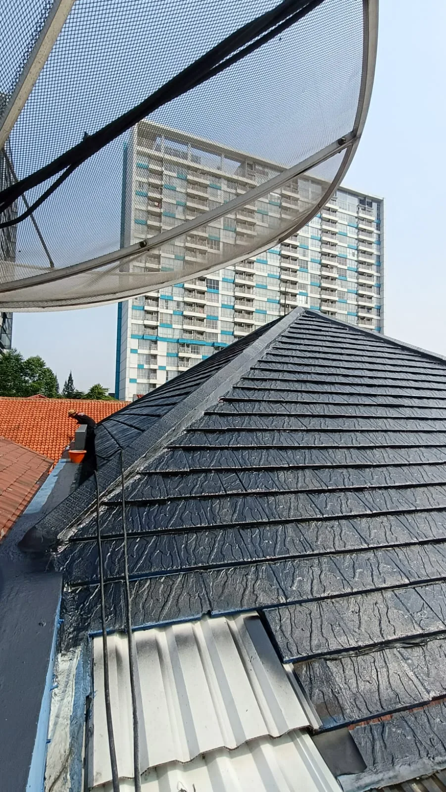 Pekerjaan pelapisan berwarna hitam pada atap genteng beton di UKI.